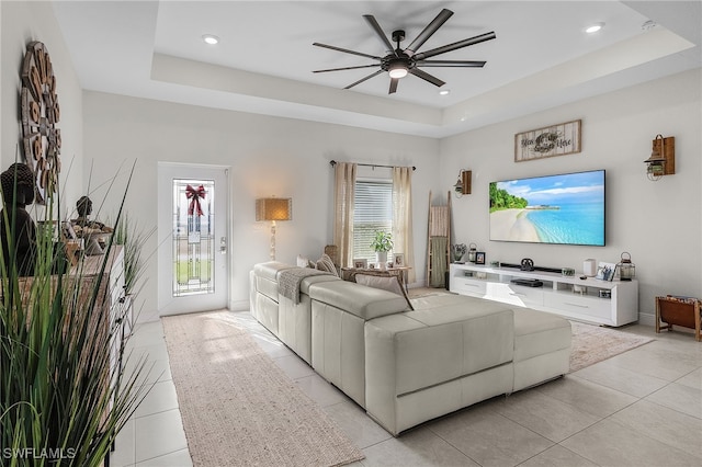 living room featuring a raised ceiling, light tile patterned flooring, and a healthy amount of sunlight