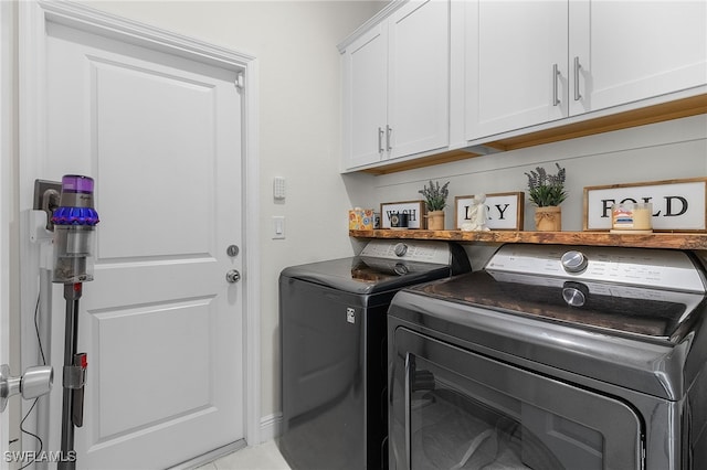 clothes washing area featuring cabinets, independent washer and dryer, and light tile patterned floors