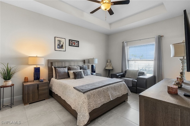 tiled bedroom with ceiling fan and a raised ceiling