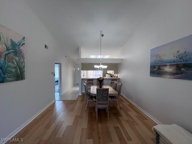 dining space featuring light hardwood / wood-style floors, a towering ceiling, and a chandelier