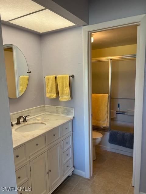 bathroom featuring toilet, tile patterned flooring, an enclosed shower, and vanity