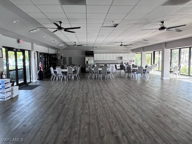 unfurnished dining area with dark wood-type flooring, a paneled ceiling, visible vents, and a ceiling fan