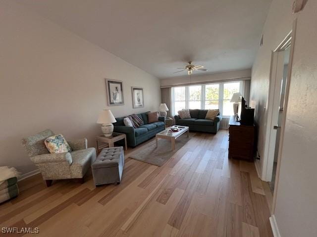 living room with a ceiling fan, vaulted ceiling, and light wood finished floors