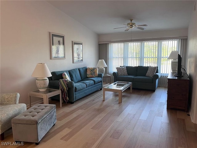 living area with ceiling fan, vaulted ceiling, and light wood-style flooring