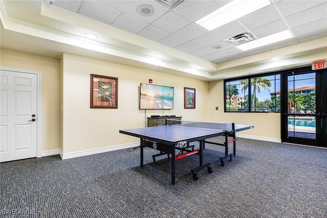 rec room featuring a drop ceiling, dark carpet, and a raised ceiling