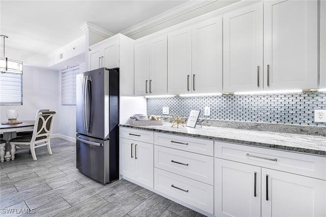 kitchen featuring white cabinets, stainless steel fridge, ornamental molding, tasteful backsplash, and light stone counters