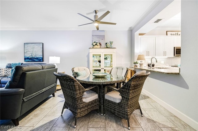 dining space with crown molding, sink, and ceiling fan