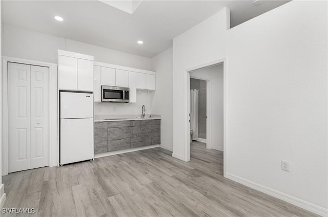 kitchen featuring white cabinets, sink, white fridge, and light wood-type flooring