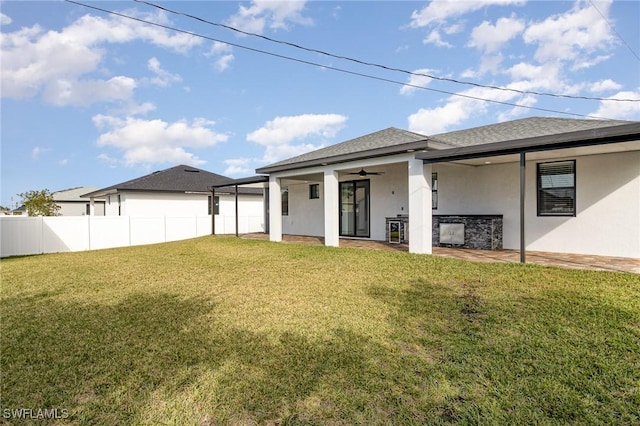 rear view of property featuring ceiling fan, a patio area, and a lawn