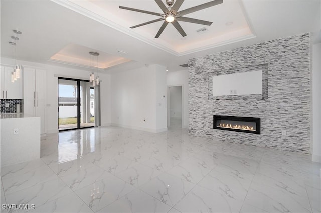 unfurnished living room with a tray ceiling, a tile fireplace, ceiling fan, and ornamental molding