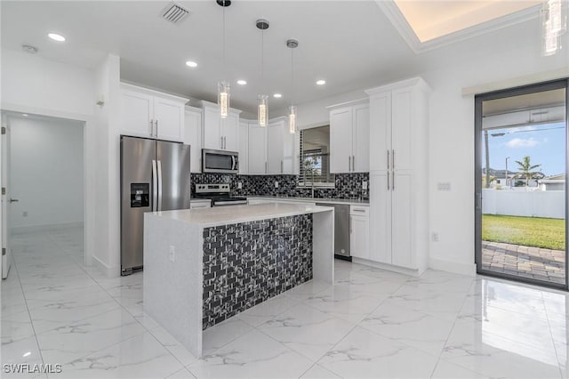 kitchen featuring a center island, white cabinets, decorative light fixtures, and appliances with stainless steel finishes