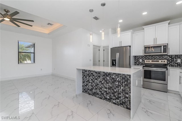 kitchen with decorative backsplash, appliances with stainless steel finishes, pendant lighting, a center island, and white cabinetry