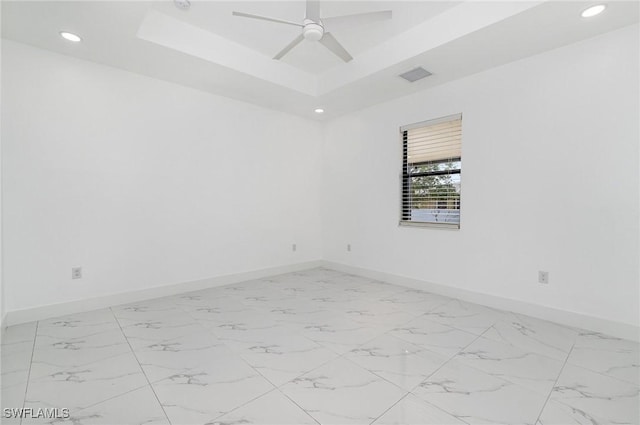 empty room featuring a raised ceiling and ceiling fan