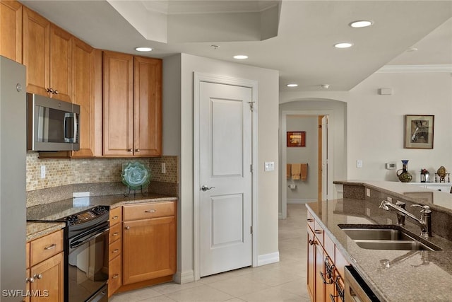 kitchen featuring appliances with stainless steel finishes, ornamental molding, sink, light tile patterned floors, and stone counters