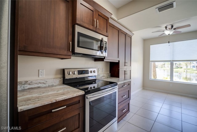 kitchen featuring light stone counters, light tile patterned floors, stainless steel appliances, and ceiling fan