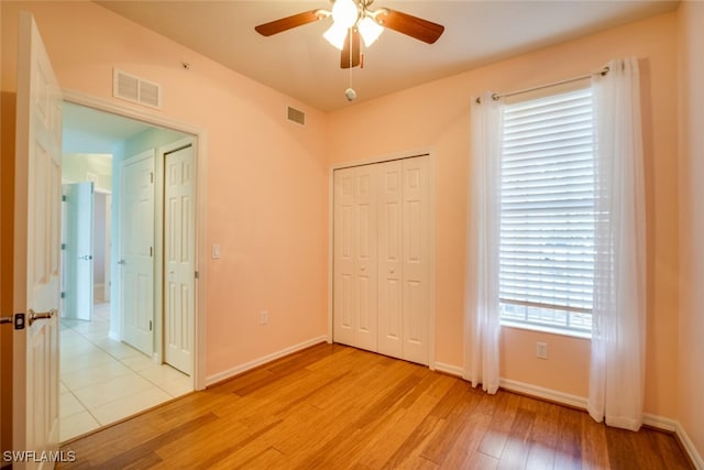 unfurnished bedroom featuring a closet, light hardwood / wood-style floors, and ceiling fan