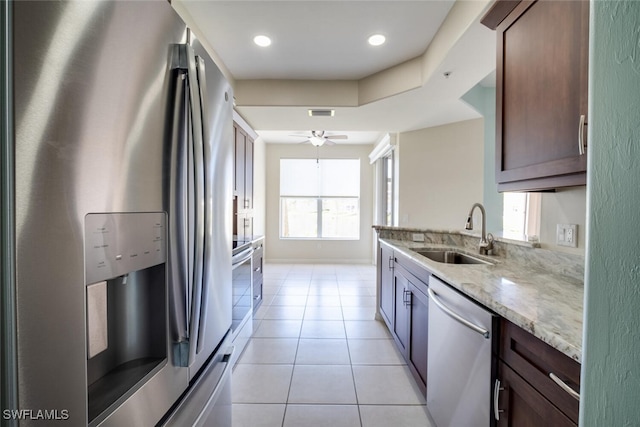 kitchen with light stone countertops, sink, ceiling fan, stainless steel appliances, and light tile patterned floors