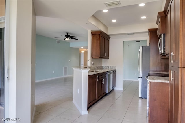 kitchen with light stone countertops, appliances with stainless steel finishes, ceiling fan, sink, and light tile patterned floors