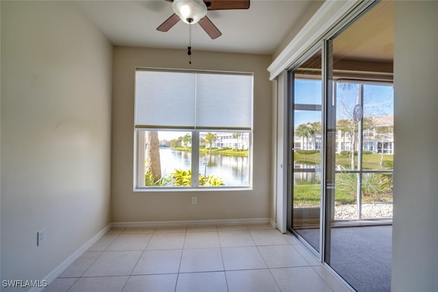 tiled spare room with ceiling fan and a water view