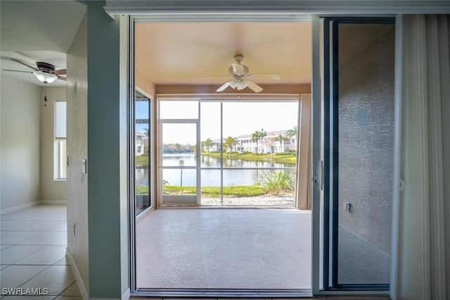 entryway with ceiling fan, a water view, light tile patterned floors, and a wealth of natural light