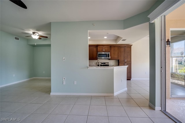 kitchen featuring ceiling fan, light tile patterned flooring, kitchen peninsula, and appliances with stainless steel finishes