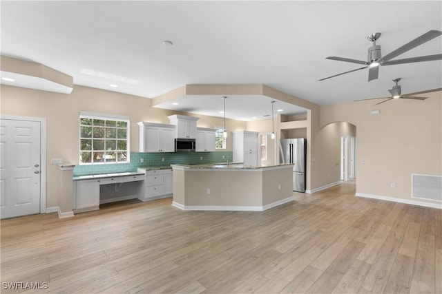 kitchen with hanging light fixtures, appliances with stainless steel finishes, decorative backsplash, white cabinets, and light wood-type flooring