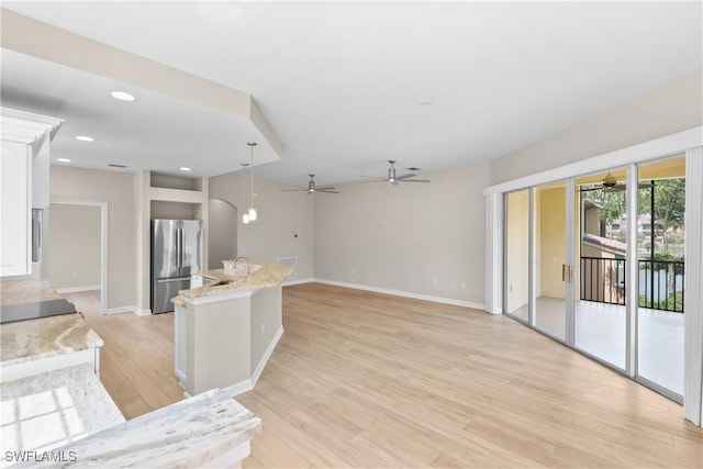 kitchen with stainless steel refrigerator, light stone countertops, light hardwood / wood-style flooring, pendant lighting, and white cabinets