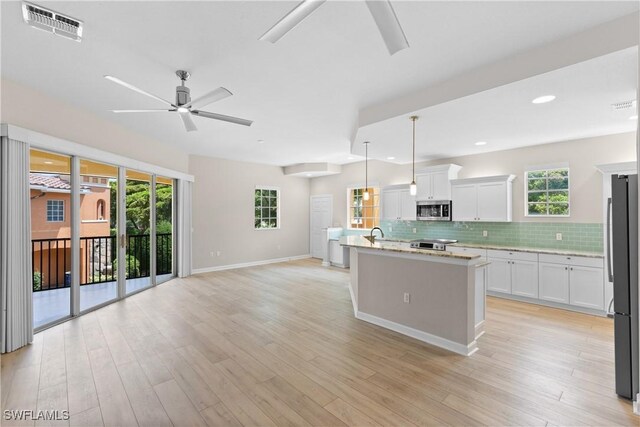 kitchen with a kitchen island with sink, white cabinets, ceiling fan, decorative light fixtures, and stainless steel appliances