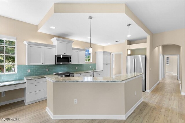 kitchen featuring white cabinets, decorative light fixtures, a kitchen island, and stainless steel appliances