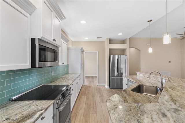 kitchen with light stone counters, sink, white cabinets, and appliances with stainless steel finishes