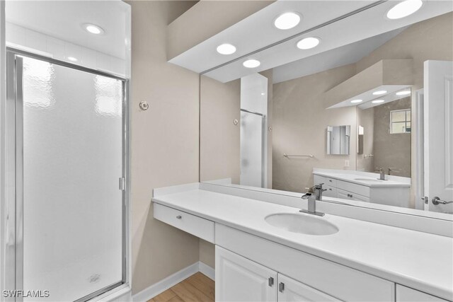 bathroom with hardwood / wood-style floors, vanity, and a shower with door