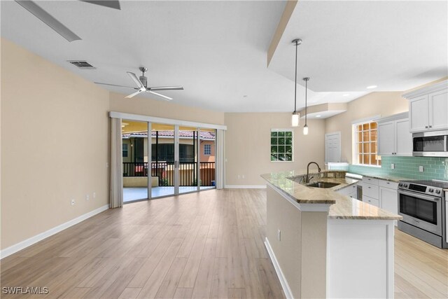 kitchen featuring pendant lighting, decorative backsplash, light stone counters, white cabinetry, and stainless steel appliances