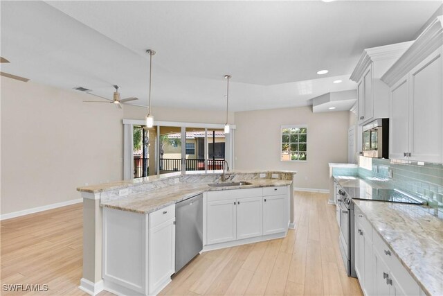 kitchen with backsplash, stainless steel appliances, sink, pendant lighting, and white cabinetry