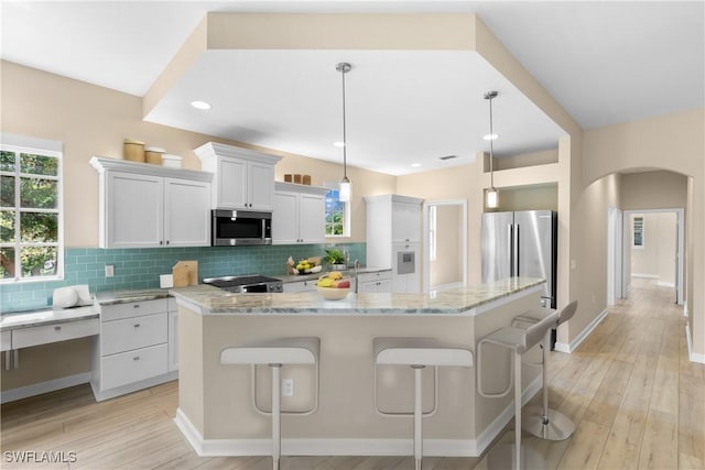 kitchen with white cabinets, a center island, decorative light fixtures, and stainless steel appliances