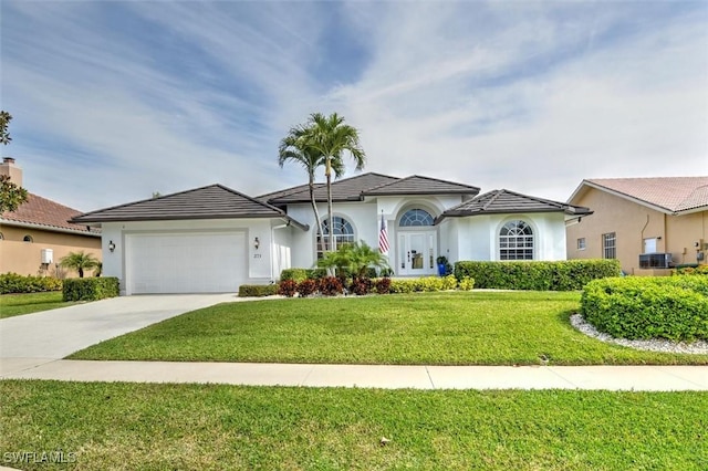 view of front facade with a front yard, central AC, and a garage