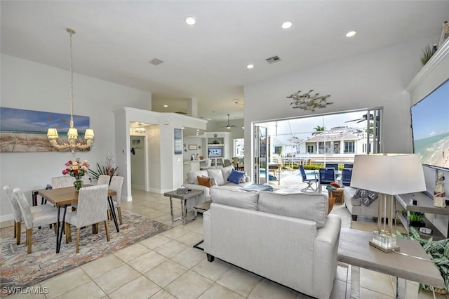 living room with a towering ceiling, a notable chandelier, and light tile patterned flooring