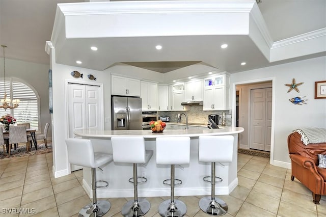 kitchen with a breakfast bar, white cabinets, appliances with stainless steel finishes, tasteful backsplash, and light tile patterned flooring