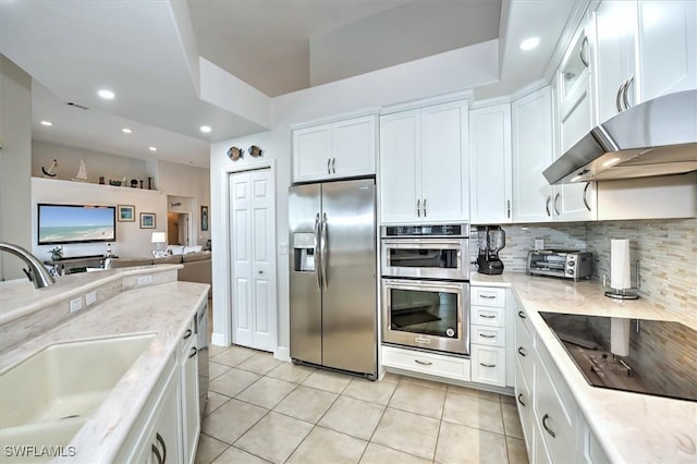 kitchen with light stone countertops, white cabinetry, sink, stainless steel appliances, and light tile patterned floors