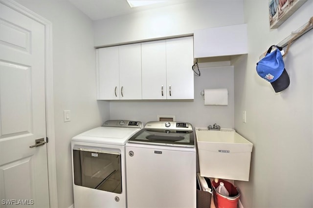 clothes washing area with cabinets, washing machine and clothes dryer, and sink