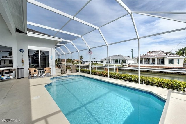 view of swimming pool featuring glass enclosure, a water view, and a patio