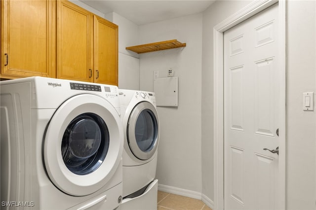 clothes washing area featuring light tile patterned flooring, separate washer and dryer, and cabinets