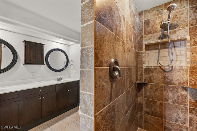 bathroom with tile patterned flooring, a tile shower, and vanity