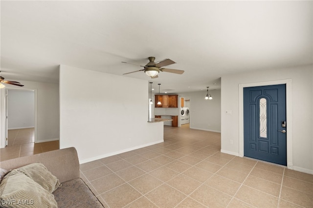 foyer featuring washer / dryer, light tile patterned flooring, and ceiling fan with notable chandelier