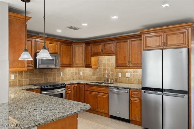 kitchen featuring sink, light stone counters, hanging light fixtures, and appliances with stainless steel finishes