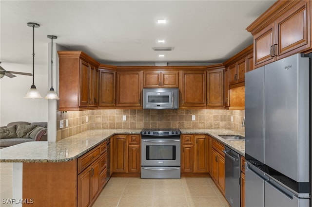 kitchen with appliances with stainless steel finishes, hanging light fixtures, light stone countertops, kitchen peninsula, and decorative backsplash