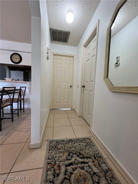 corridor with light tile patterned floors and a textured ceiling