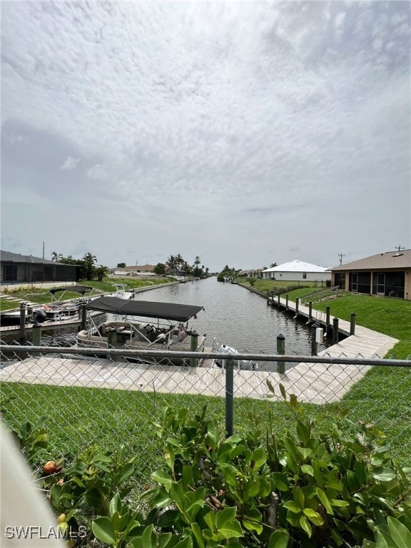 view of dock with a water view and a lawn