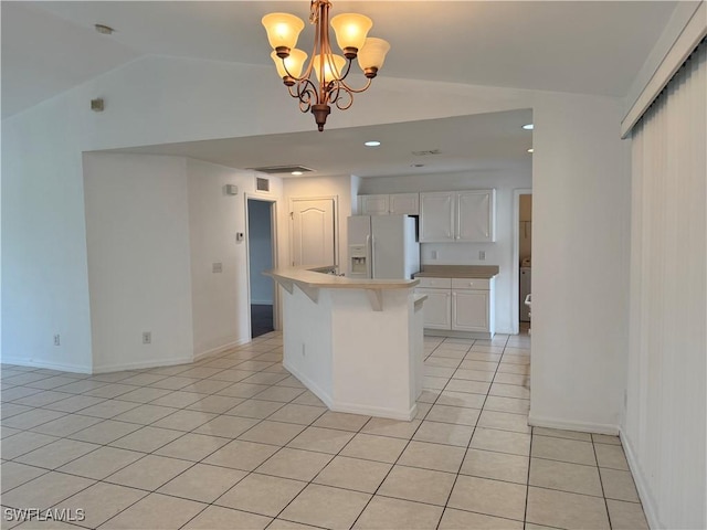 kitchen featuring white refrigerator with ice dispenser, a center island, white cabinets, an inviting chandelier, and decorative light fixtures