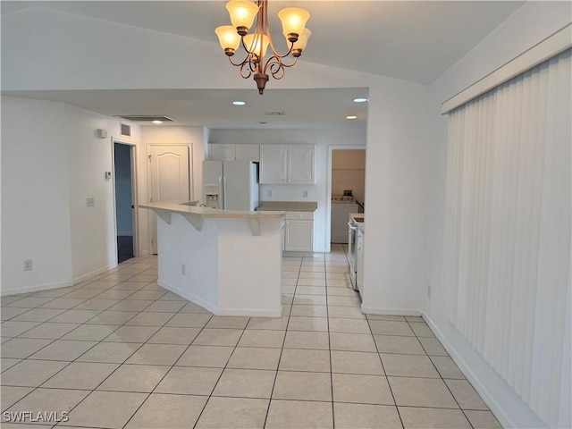 kitchen with white fridge with ice dispenser, a notable chandelier, pendant lighting, white cabinetry, and lofted ceiling