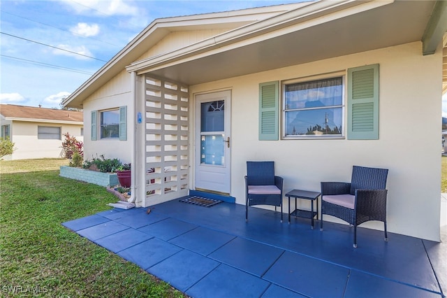 entrance to property featuring a patio area and a yard